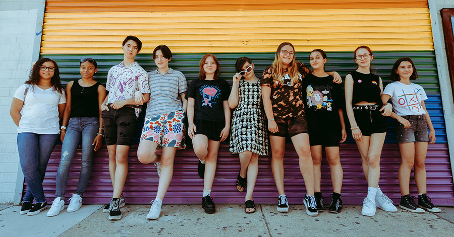 Group of teens standing in front of a rainbow painted wall