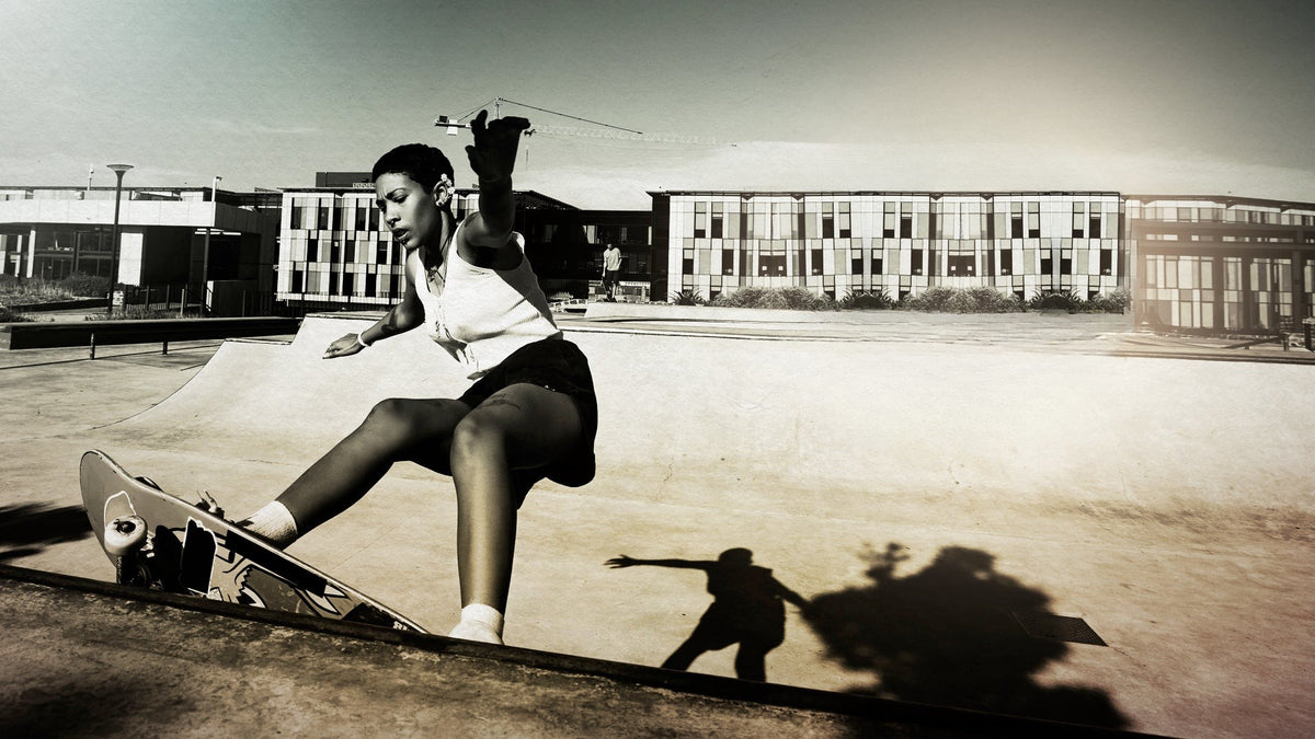 Skater in a white tank top riding a ramp at a skate park